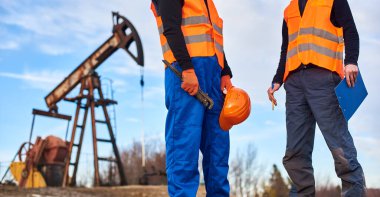 Endüstriyel ingiliz anahtarı tutan petrol operatörünü kapat, kask meslektaşının yanında.