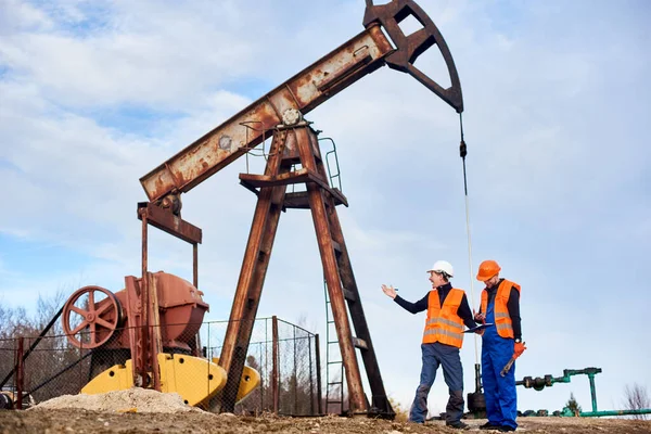 Dos Ingenieros Petroleros Con Monos Chalecos Naranjas Cascos Parados Campo —  Fotos de Stock