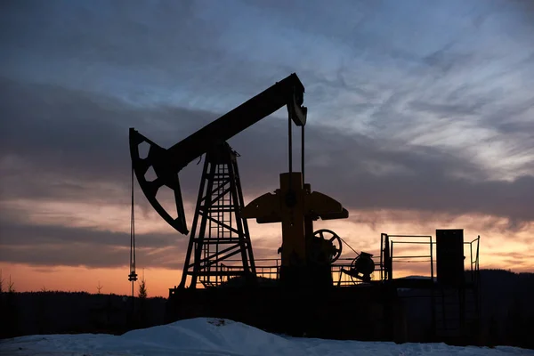 View of evening dramatic sky over long stroke balanced beam petroleum pump jack