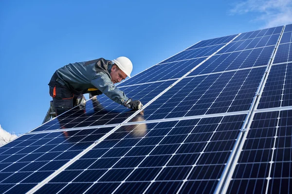 美しく光沢のある太陽電池の表面と労働者は はしごの上に立って 制服を着ている 晴れた日に太陽電池モジュールをインストール男性電気技師 低角度ビュー 代替エネルギーの概念 — ストック写真