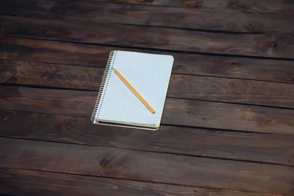 Ноутбук в клетке и желтый карандаш — стоковое фото