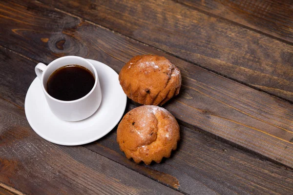 Weiße Tasse Kaffee und zwei Cupcakes auf hölzernem Hintergrund — Stockfoto
