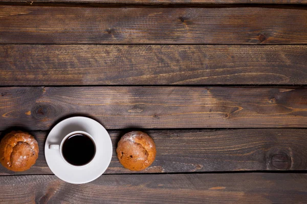 Caneca branca de café e dois cupcakes em fundo de madeira — Fotografia de Stock