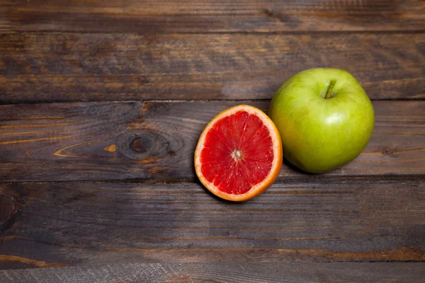 Pomme verte fraîche et pamplemousse coupé juteux sur fond de bois — Photo