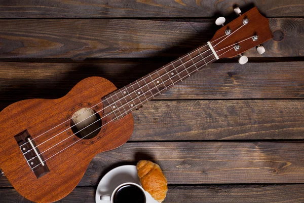 Ukulele ukulele with cup of coffee and croissant