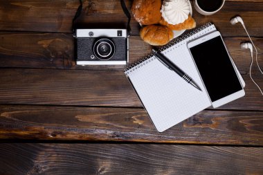 Kruvasan ve kahve yanında dizüstü kulaklık ile fotoğraf makinesi