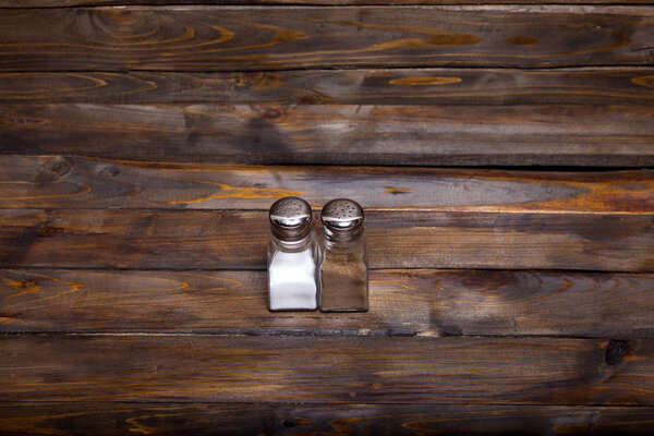 Two transparent cans of salt and pepper shaker on wooden background