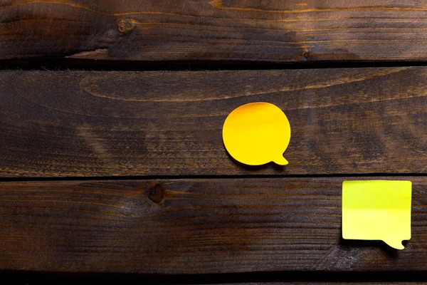 Two yellow stickers for notes and reminders on wooden background