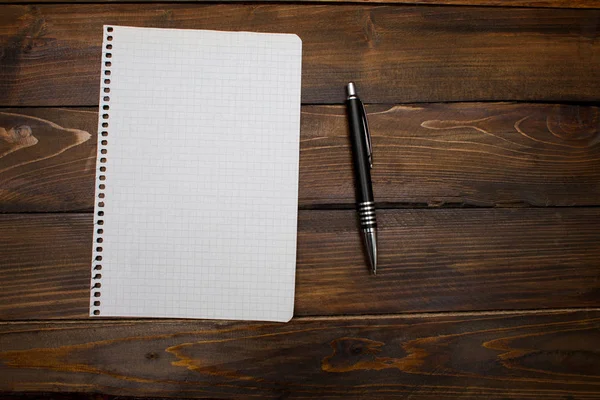 Pen with white sheet of paper in box on wooden background. Top view with copy space — Stock Photo, Image