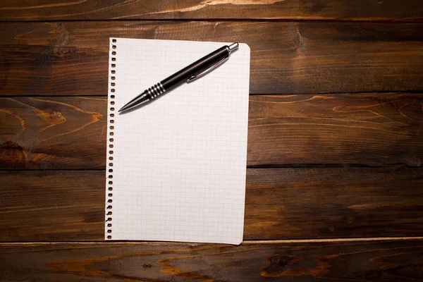 Pen with white sheet of paper in box on wooden background. Top view with copy space — Stock Photo, Image