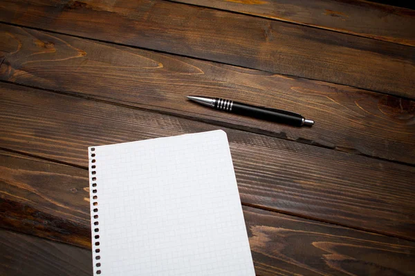 Pen with white sheet of paper in box on wooden background. Top view with copy space — Stock Photo, Image