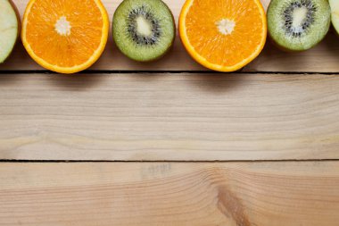 Yarım kesilmiş yeşil elma, kivi, portakal turuncu. Ahşap arka plan üzerinde sulu meyve