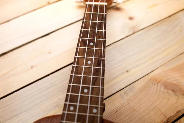 Hawaiianische viersaitige Gitarre Ukulele Nahaufnahme Bünde auf Holzgrund — Stockfoto