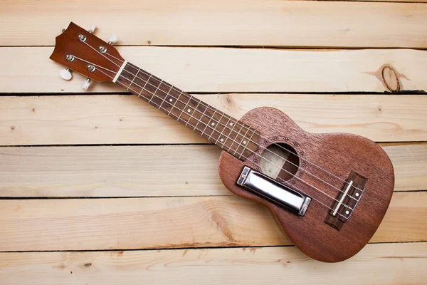 Guitarra ukelele hawaiana de cuatro cuerdas y armónica de hierro sobre fondo de madera —  Fotos de Stock
