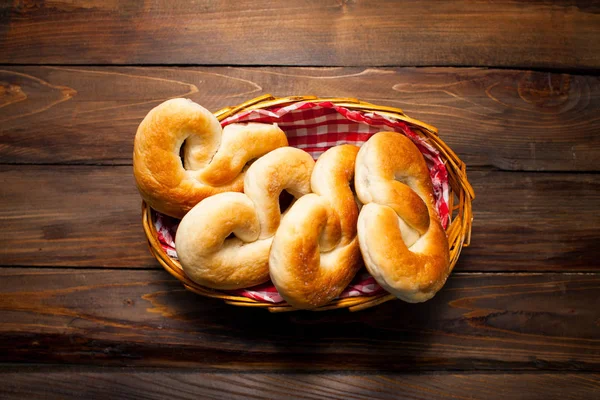 Délicieux bretzels frais dans un panier en osier sur fond de bois — Photo