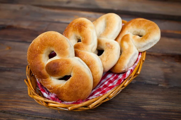 Délicieux bretzels frais dans un panier en osier sur fond de bois — Photo