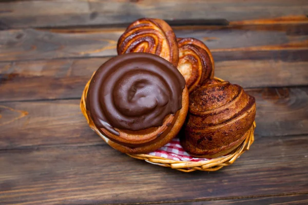 Délicieux bretzels frais au chocolat dans un panier en osier sur fond de bois — Photo