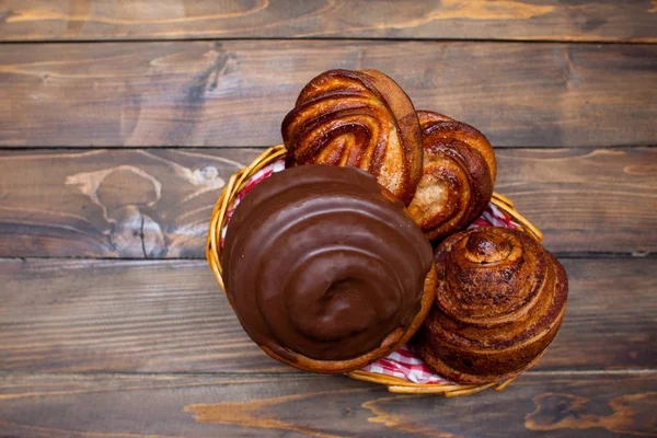 Délicieux bretzels frais au chocolat dans un panier en osier sur fond de bois — Photo