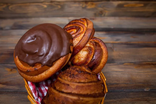 Deliciosos, pretzels frescos em chocolate em uma cesta de vime em um fundo de madeira — Fotografia de Stock