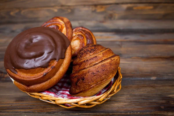 Délicieux bretzels frais au chocolat dans un panier en osier sur fond de bois — Photo