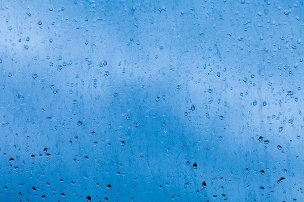 Tropfen vom Regen auf die Fensterscheibe. abstraktes Blau, kontrastierender Hintergrund mit natürlichem Wasser — Stockfoto