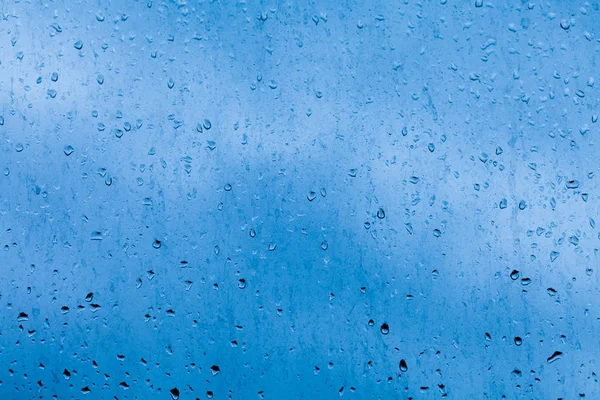 Csepp a az ablaktábla az esőtől. Absztrakt kék, kontrasztos háttérben természetes víz — Stock Fotó