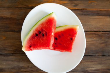 Kırmızı karpuz ahşap arka plan üzerinde. Dilim karpuz çilek beyaz bir tabak içinde