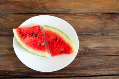 Kırmızı karpuz ahşap arka plan üzerinde. Dilim karpuz çilek beyaz bir tabak içinde