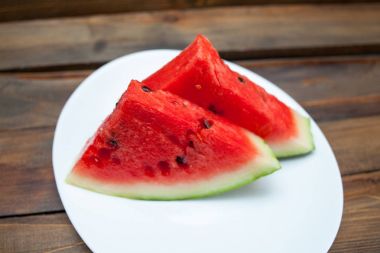 Kırmızı karpuz ahşap arka plan üzerinde. Dilim karpuz çilek beyaz bir tabak içinde