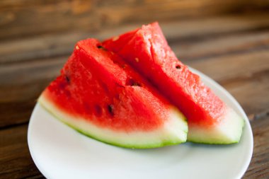 Kırmızı karpuz ahşap arka plan üzerinde. Dilim karpuz çilek beyaz bir tabak içinde