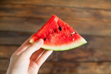 Sulu karpuz önünde bir yumru holding insan eller. Ahşap arka plan
