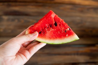 Sulu karpuz önünde bir yumru holding insan eller. Ahşap arka plan