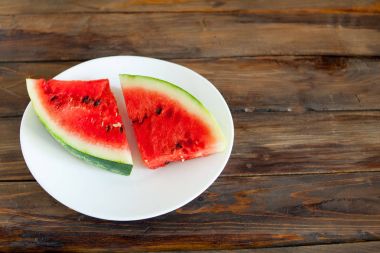 Kırmızı karpuz ahşap arka plan üzerinde. Dilim karpuz çilek beyaz bir tabak içinde