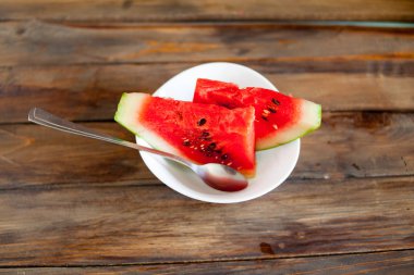 Kırmızı karpuz ahşap arka plan üzerinde. Dilim karpuz çilek bir kaşık beyaz bir tabak içinde