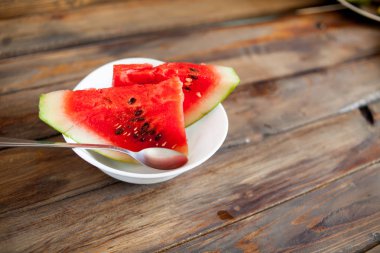 Kırmızı karpuz ahşap arka plan üzerinde. Dilim karpuz çilek bir kaşık beyaz bir tabak içinde
