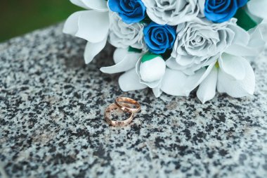 Altın alyans mermer taşıyla gelini kağıttan, yapay beyaz çiçek bir buket üzerinde