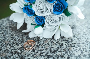 Altın alyans mermer taşıyla gelini kağıttan, yapay beyaz çiçek bir buket üzerinde