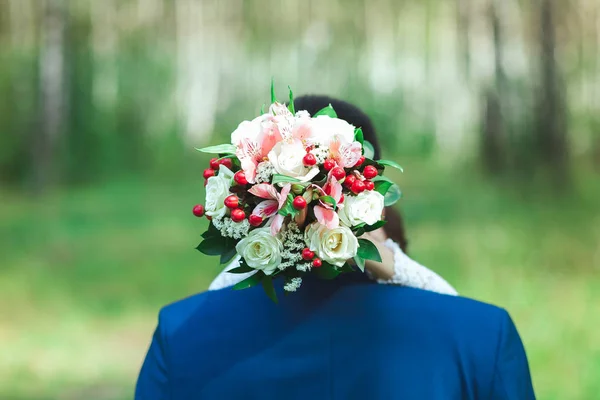 The bride is hugging the groom by the neck. A girl is holding a wedding bouquet — Stock Photo, Image