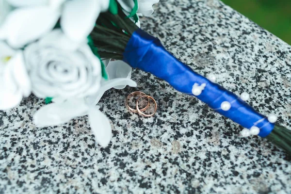 Altın alyans mermer taşıyla gelini kağıttan, yapay beyaz çiçek bir buket üzerinde