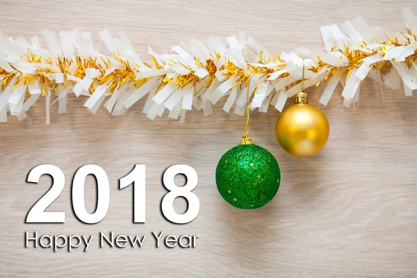 Bolas de Año Nuevo de colores brillantes y una guirnalda sobre un fondo de madera clara con la inscripción Feliz Año Nuevo 2018 — Foto de Stock