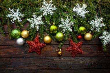 Yeni yıl yeşil, sarı ve gümüş toplar ve beyaz kar taneleri bir ahşap zemin üzerine canlı çam dalları ile birlikte kırmızı yıldızlar. Üstten Görünüm