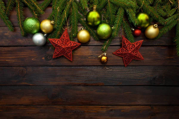 Nowy rok zieleni, żółte i srebrne kule czerwone gwiazdy wraz z gałęzi jodły na żywo na tle drewnianych. Widok z góry — Zdjęcie stockowe
