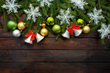 Yeşil çam dalları koyu ahşap arka plan üzerinde yaşayan. Yeni yıl arka plan güzel topları ve beyaz kar ve çan ile. Üstten Görünüm