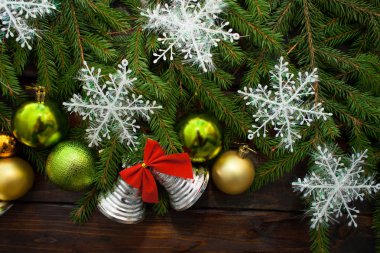 Yeşil çam dalları koyu ahşap arka plan üzerinde yaşayan. Yeni yıl arka plan güzel topları ve beyaz kar ve çan ile. Üstten Görünüm
