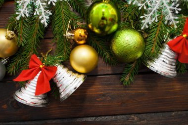 Yeşil çam dalları koyu ahşap arka plan üzerinde yaşayan. Yeni yıl arka plan güzel topları ve beyaz kar ve çan ile. Üstten Görünüm