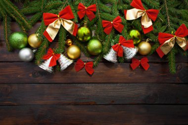 Yeşil çam dalları koyu ahşap arka plan üzerinde yaşayan. Yeni yıl arka plan güzel topları ve kırmızı ok ve çan. Üstten Görünüm