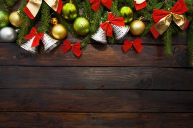 Yeşil çam dalları koyu ahşap arka plan üzerinde yaşayan. Yeni yıl arka plan güzel topları ve kırmızı ok ve çan. Üstten Görünüm