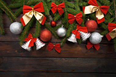 Yeşil çam dalları koyu ahşap arka plan üzerinde yaşayan. Yeni yıl arka plan güzel topları ve kırmızı ok ve çan. Üstten Görünüm