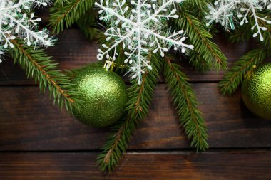 Yeşil çam dalları koyu ahşap arka plan üzerinde yaşayan. Yeşil topları ve beyaz kar taneleri ile yeni yıl arka plan. Üstten Görünüm