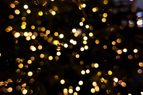 Yellow lights of a tree garland. Abstract blurred Christmas background, bokeh. Glowing light bulbs